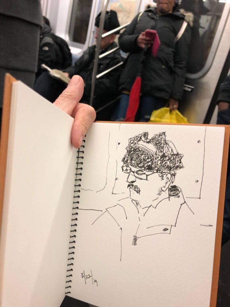 A person holding up an open book with a drawing of a man.