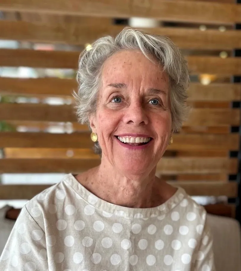 Smiling woman with short gray hair indoors.